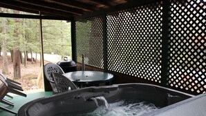 Een bubbelbad met stromend water, een tafel, stoelen en een houten schutting in een overdekte buitenruimte.