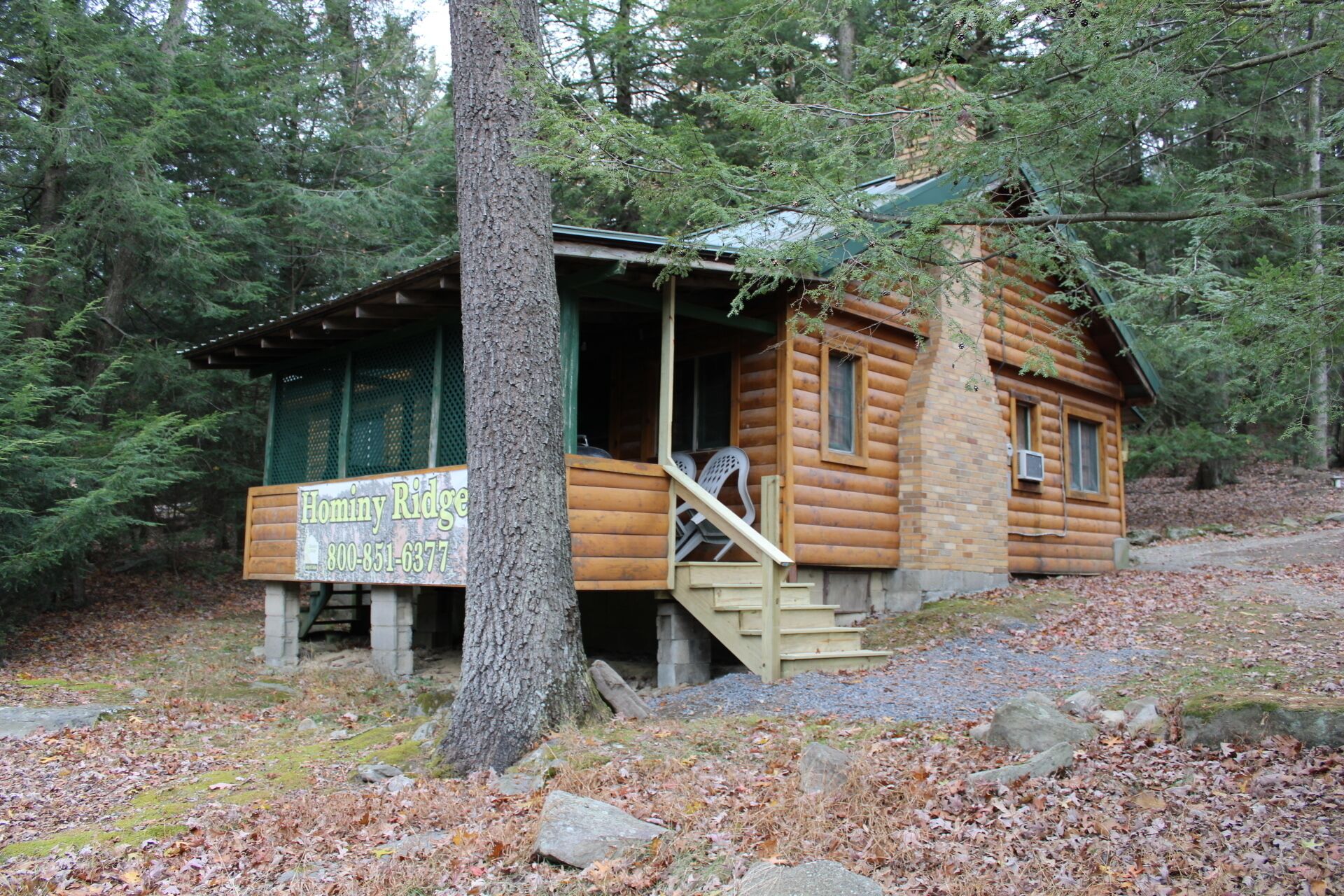 A rustic cabin with a porch, a signboard, and a staircase leading to the entrance.