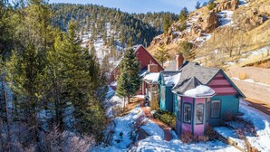 Un paisaje nevado con un grupo de casas coloridas, una zona boscosa y una montaña al fondo.