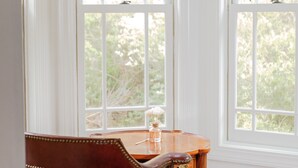 Una habitación con una silla de madera y una mesa cerca de una ventana con persianas blancas.