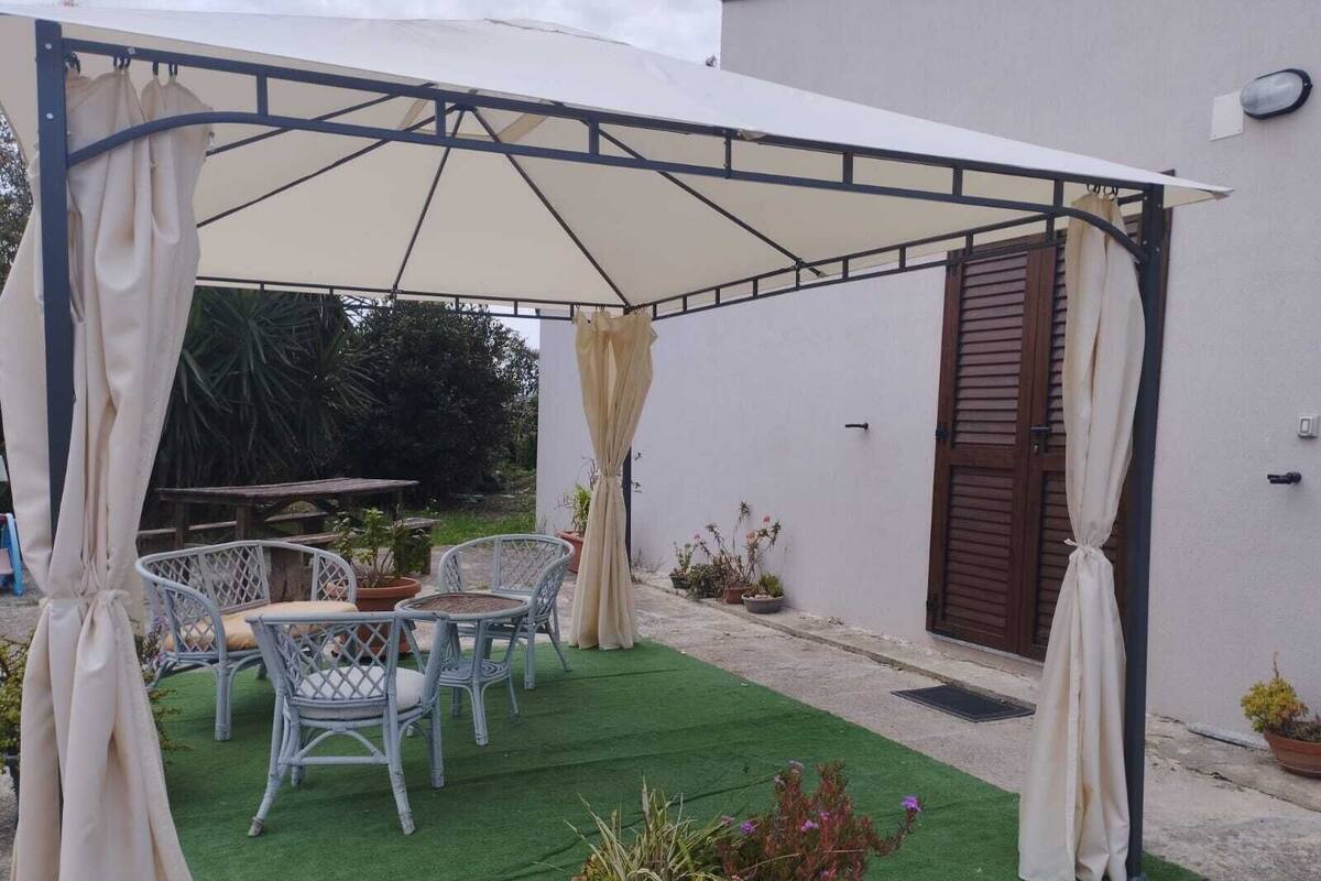 A covered patio area with outdoor furniture and potted plants.