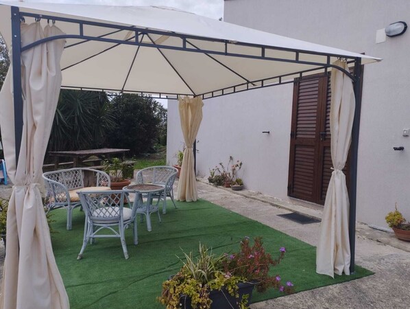 Un patio cubierto con mobiliario exterior y plantas en macetas.