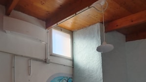 Egy szoba, amelyben van egy étkezőasztal, székek, egy mennyezeti ventilátor, egy ablak és egy falfestmény, amely egy fát ábrázol.