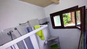 Egy kis fürdőszoba zuhanyzóval, WC-vel és egy ablakkal.