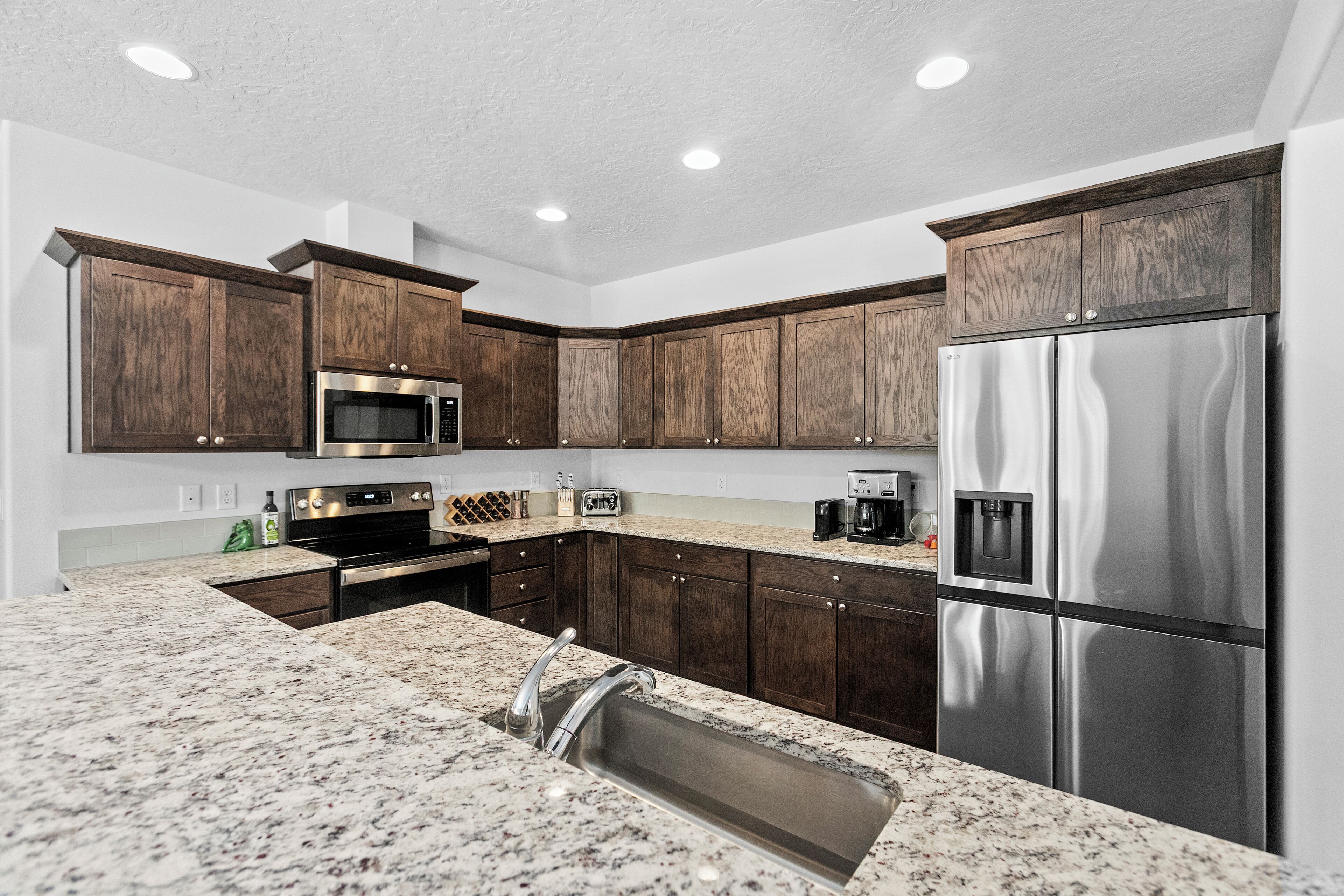 A kitchen with dark wooden cabinets, stainless steel appliances, and granite countertops.
