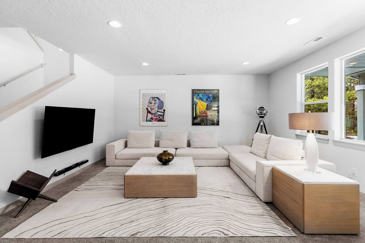 A modern living room with a flat-screen TV, a sectional sofa, a coffee table, and artwork on the walls.