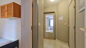 Een slaapkamer met een bed, een houten garderobe en een deur naar een badkamer.