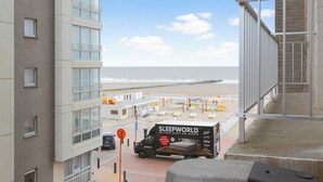 Uitzicht op een hotel aan het strand, met een Sleepworld vrachtwagen ervoor geparkeerd, met zicht op het strand en de oceaan.
