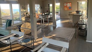 A spacious living area with a high ceiling, large windows, and a view of the outdoors. - Fire Island Pines Oasis w/4 King Bdrms, Heated Pool, Hot Tub, Ocean & Bay Views (Sayville)