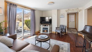 A living room with a fireplace, a television, and a sliding glass door leading to a patio.