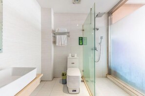 Une salle de bain moderne avec une douche à parois de verre, des toilettes blanches et une grande baignoire.