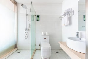 Une salle de bain moderne avec une douche à parois de verre, des toilettes blanches et un lavabo avec un miroir.