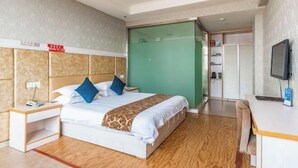 A hotel room with a bed, a desk, a television, and a green sliding door.