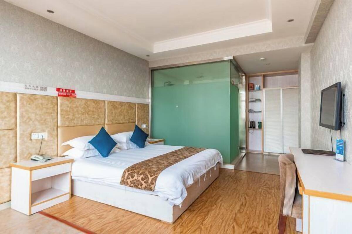 A hotel room with a bed, a desk, a television, and a green sliding door.