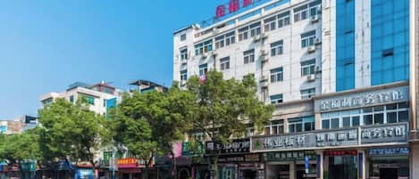 A multi-story hotel with a modern facade, located on a busy street with various shops and pedestrians.