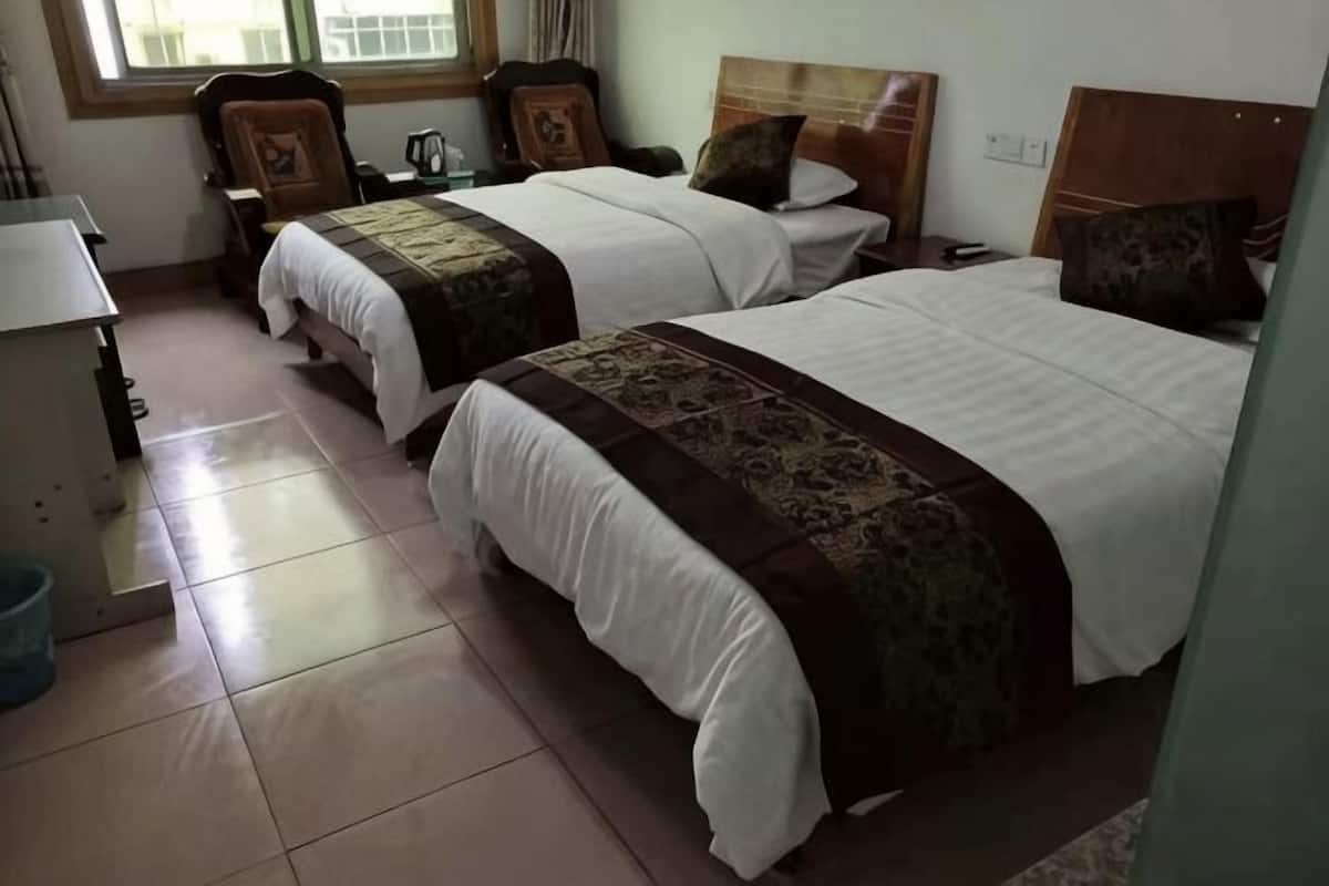 Une chambre dâhĂŽtel avec deux lits, un bureau, une chaise et une fenĂȘtre.