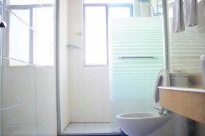 Une salle de bain comprenant des toilettes, un lavabo et un espace douche.