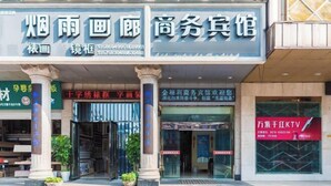 A building with a sign that reads "烟雨画廊 商务宾馆" and "千学绣球馆 学画阁".