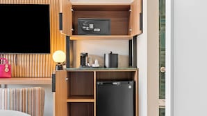 Una kitchenette compacta con microondas, cafetera y refrigerador.