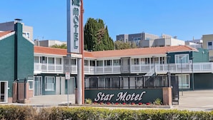 Un motel Star con un letrero llamativo, un balcón y una chimenea alta.