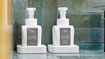 Two white pump bottles of lotion and soap on a marble surface.