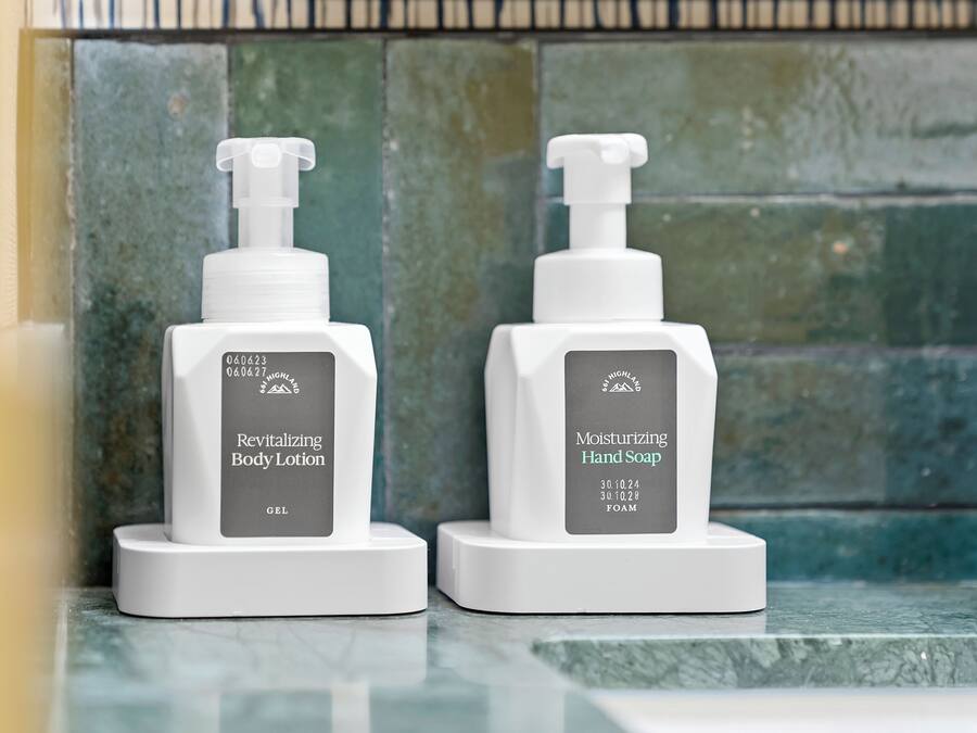 Two white pump bottles of lotion and soap on a marble surface.