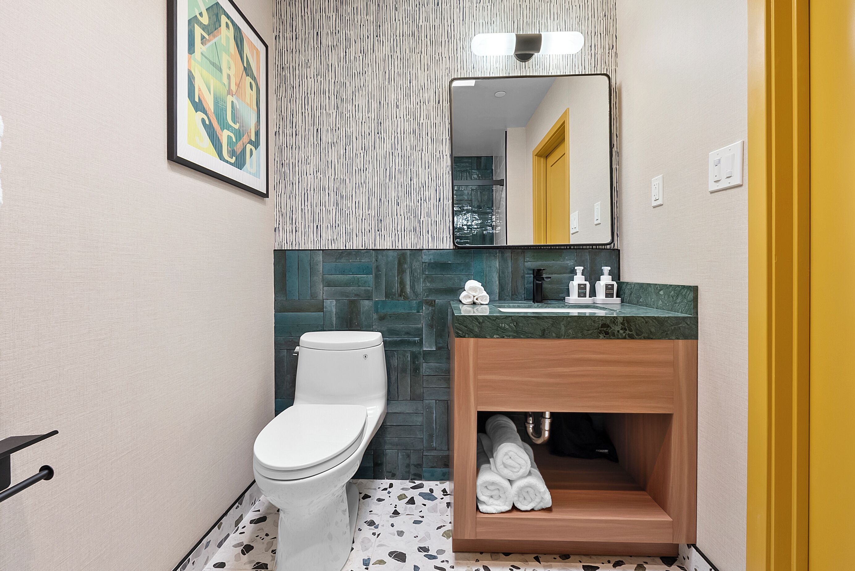 A modern bathroom with a white toilet, a wooden vanity, and a mirror.