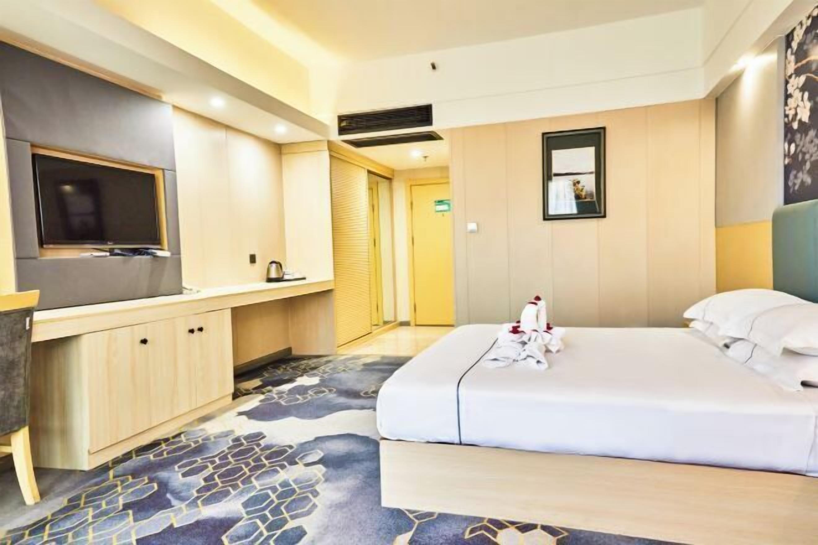 Une chambre d’hôtel avec un lit, une télévision, un bureau et une porte de salle de bain.