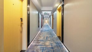 A hotel hallway with a long corridor, doors on both sides, and a patterned floor. - Magnotel Hotel (Yichang CBD Shopping Center) (Yichang)