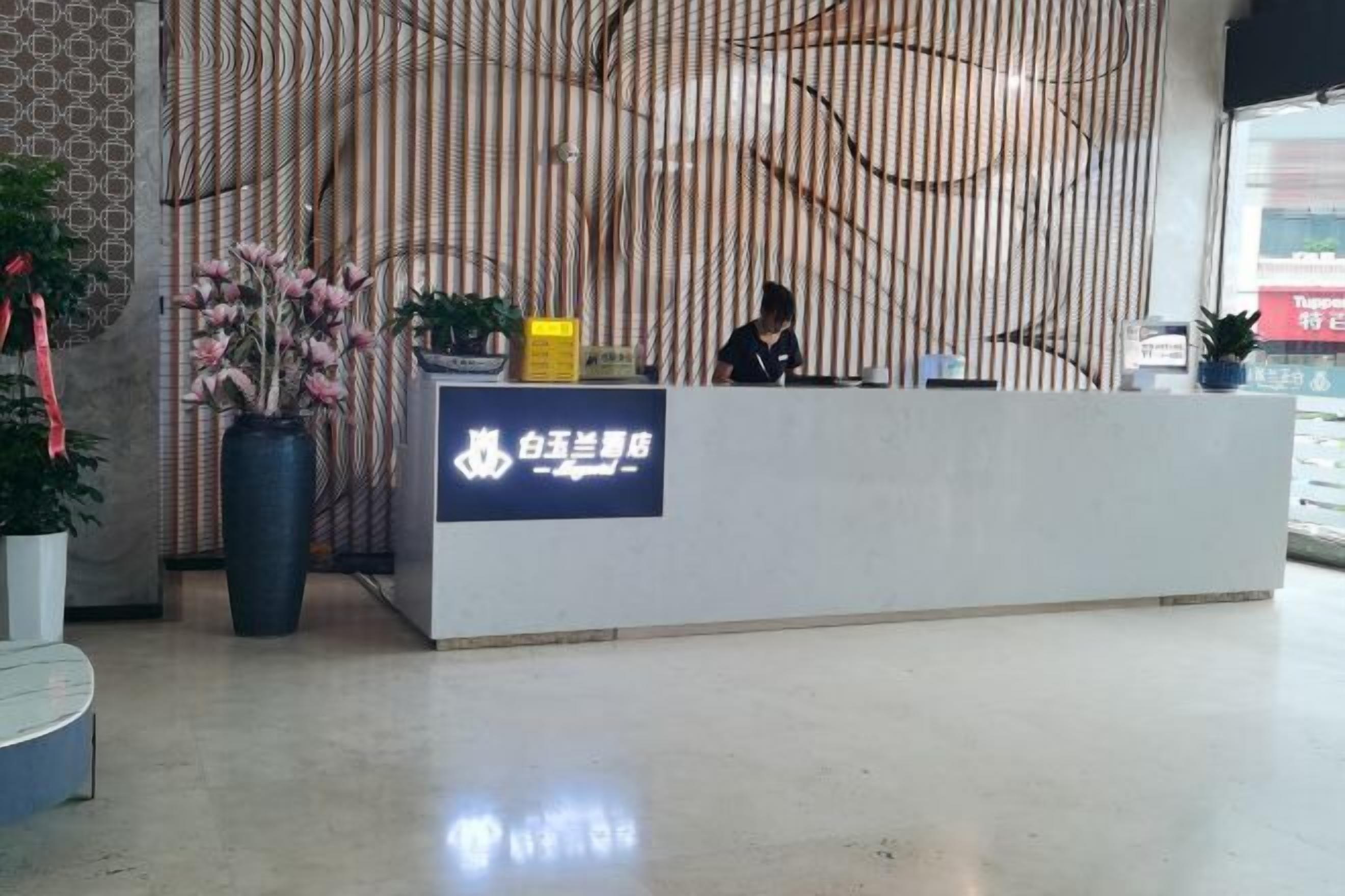 A reception desk with a sign, a potted plant, and a vertical bamboo screen in the background.