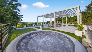 Ein Whirlpool, umgeben von einer überdachten Terrasse mit Sitzgelegenheiten und Blick auf die Landschaft.