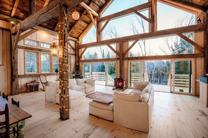 A spacious room with wooden beams, large windows, and a cozy seating area with white furniture. - Gorgeous couples barn with WiFi & hot tub in lovely Londonderry (Londonderry)