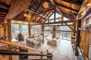 Eine geräumige Holzhütte mit hohen Decken, großen Fenstern, einem Essbereich und einem gemütlichen Wohnzimmer.