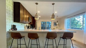 A modern kitchen with a central island, bar stools, pendant lights, and wooden cabinets. - Charming 4-bedroom house with AC and WiFi in awesome Crestline (Crestline)