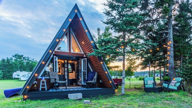 A triangular A-frame cabin with a deck, seating area, and string lights. - A FRAME ALPHA -WoW This Old Tree
 (Five Islands)