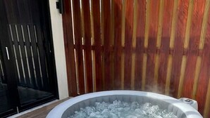 Uma banheira de hidromassagem redonda com exterior de madeira, identificada como 'SALUSPA', colocada ao ar livre em um deck de madeira.