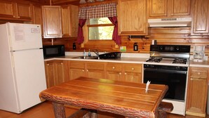 Une cuisine avec des meubles de rangement en bois, un réfrigérateur, un four à micro-ondes, une cuisinière et un évier.