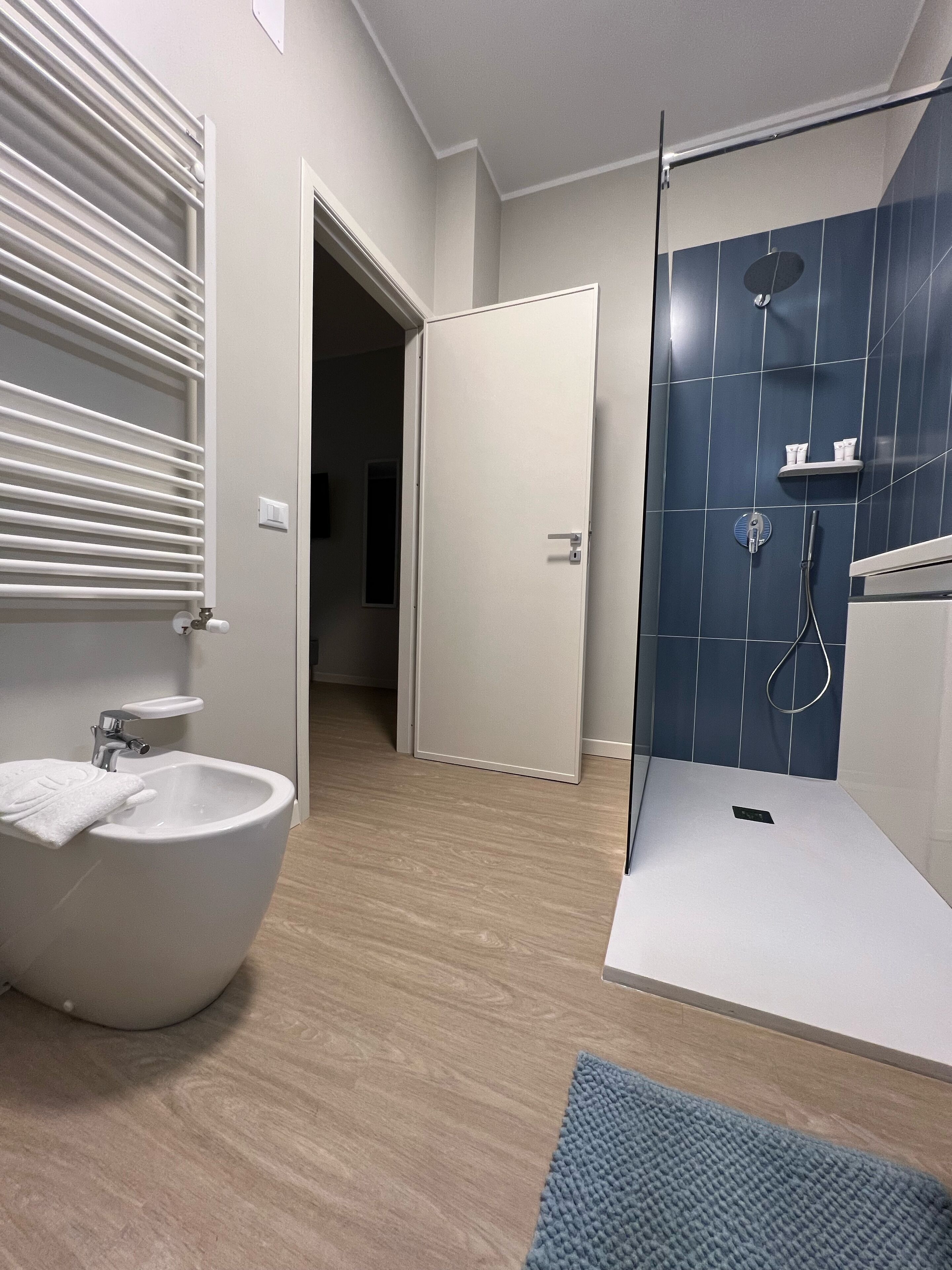 Uma casa de banho moderna com uma banheira independente, um lavatório com uma toalha e uma área de chuveiro com azulejos azuis.