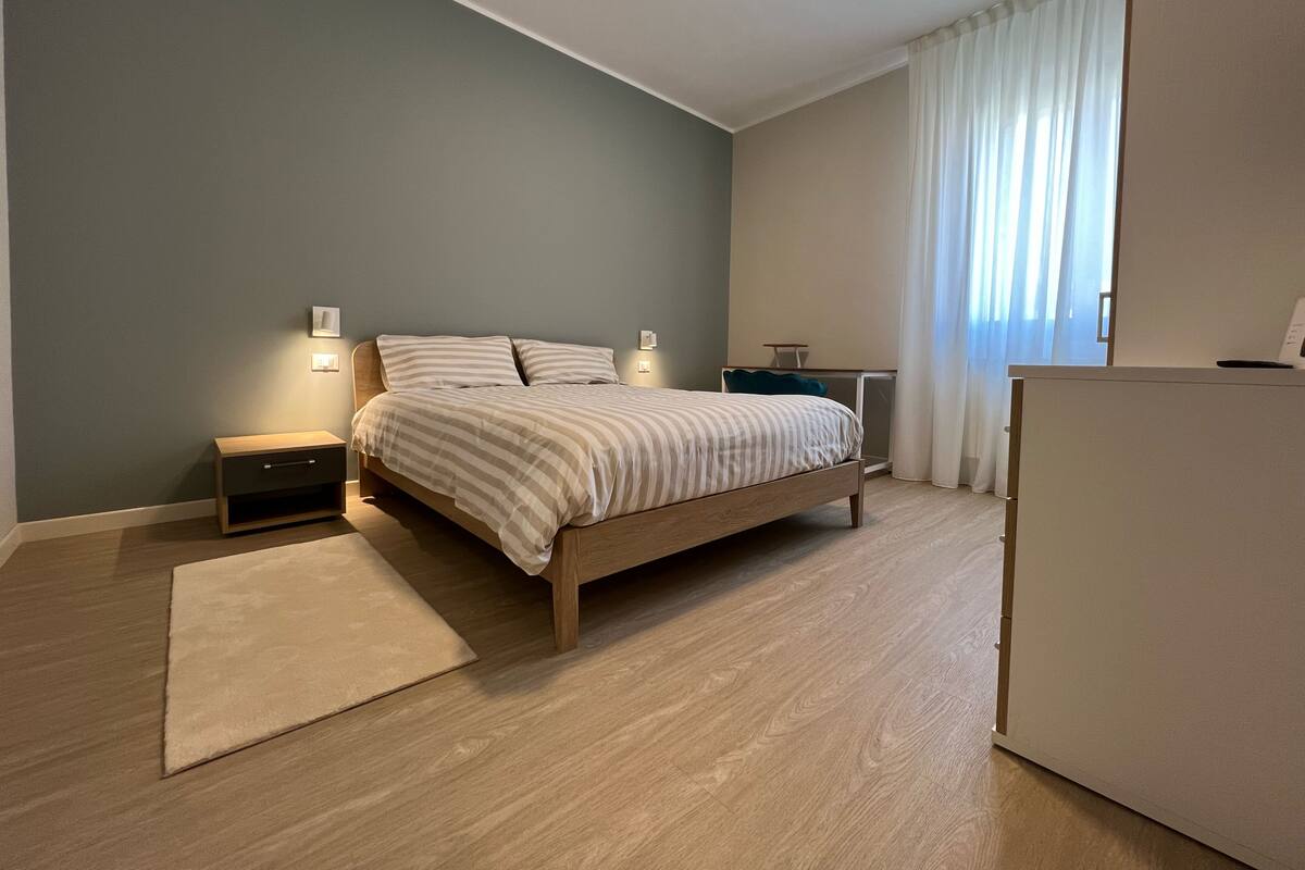 A bedroom with a bed, bedside tables, a desk, and a wardrobe.