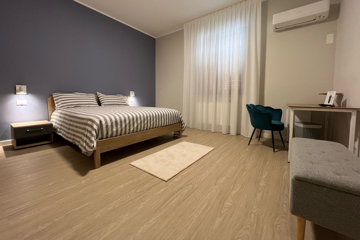 A modern bedroom with a bed, bedside tables, a desk, and a chair.