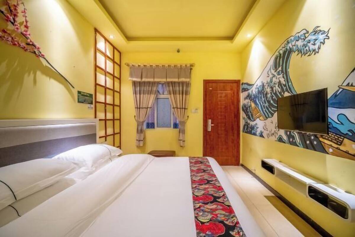 Ein Hotelzimmer mit einem Bett, einem Fernseher, einem Fenster mit Vorhängen und einer Wand mit einem Wellenbild.