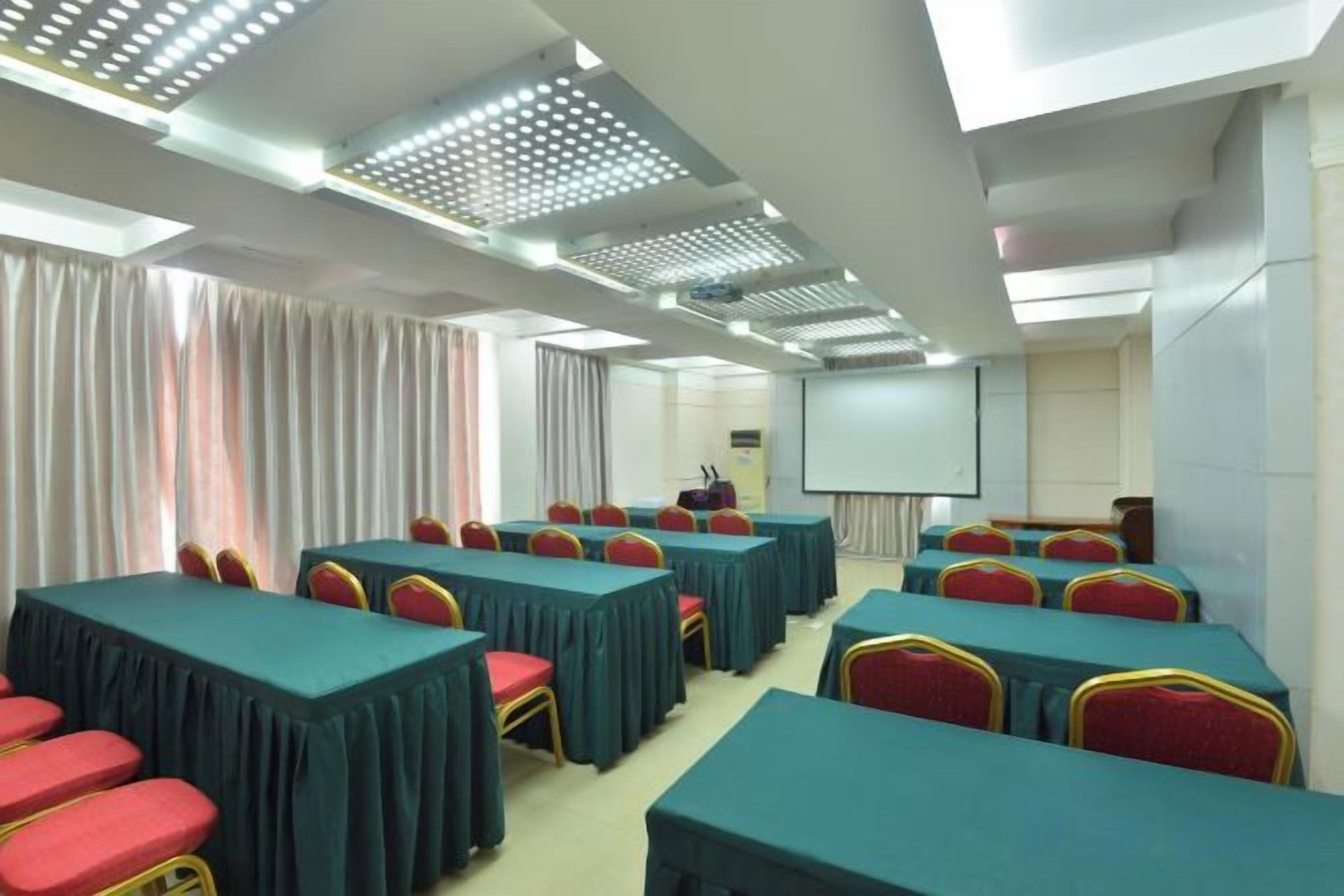 A conference room with tables and chairs, a projector screen, and a whiteboard.