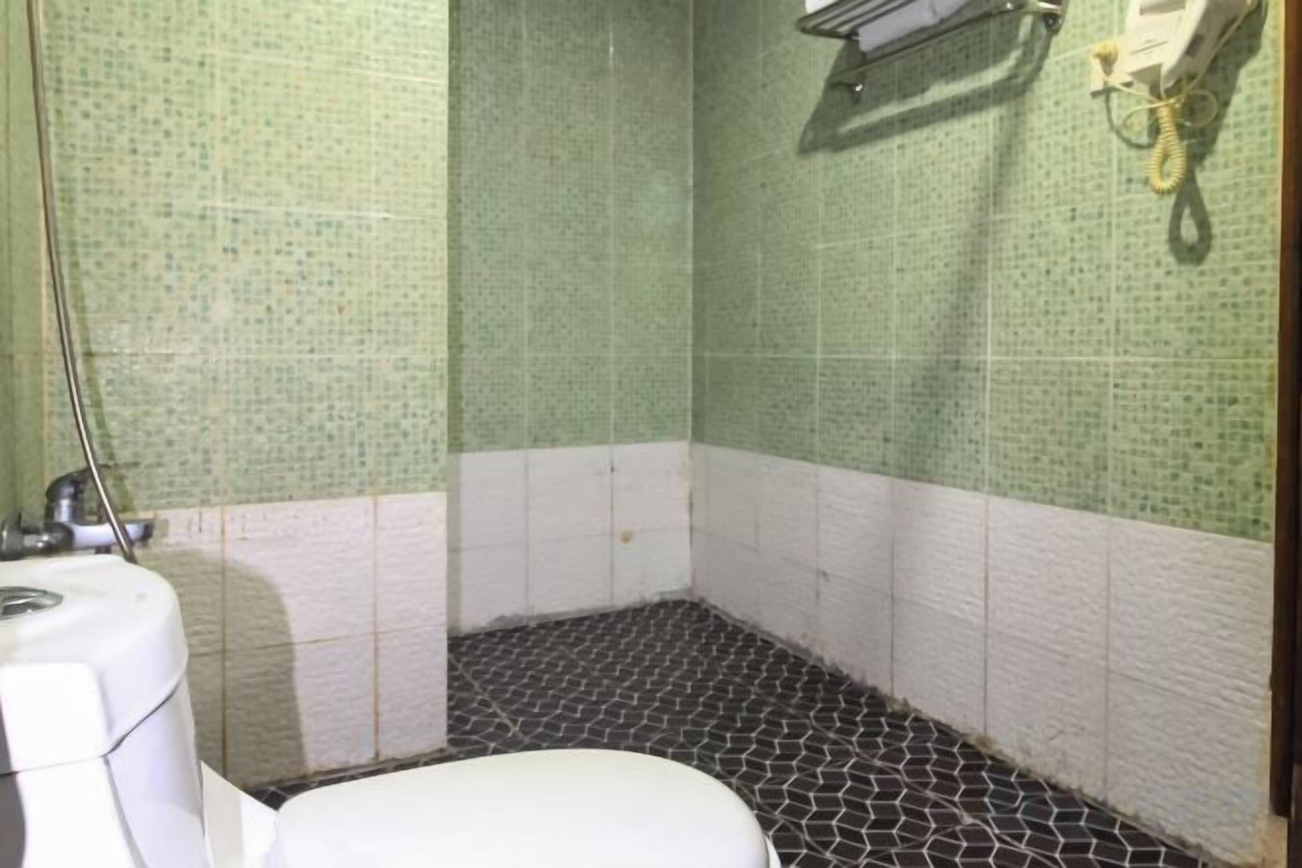 A bathroom with a toilet, a shower, and a tiled floor.