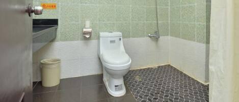 A bathroom with a toilet, a shower, and a tiled floor.