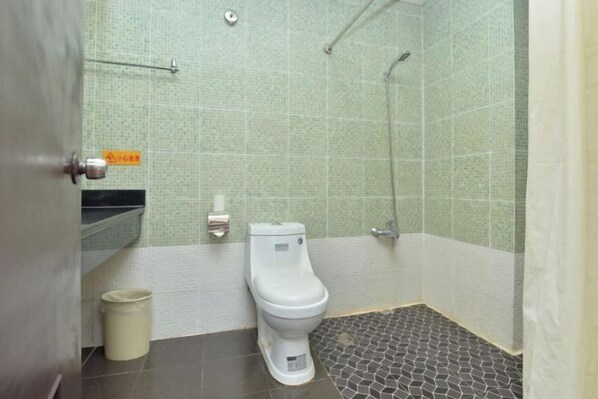 Un baño con inodoro, ducha y piso de baldosas.