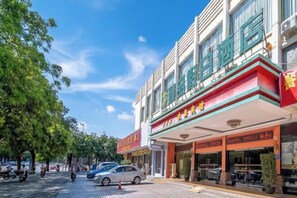 Un hotel con fachada roja y verde, grandes ventanales y un cartel con caracteres chinos.