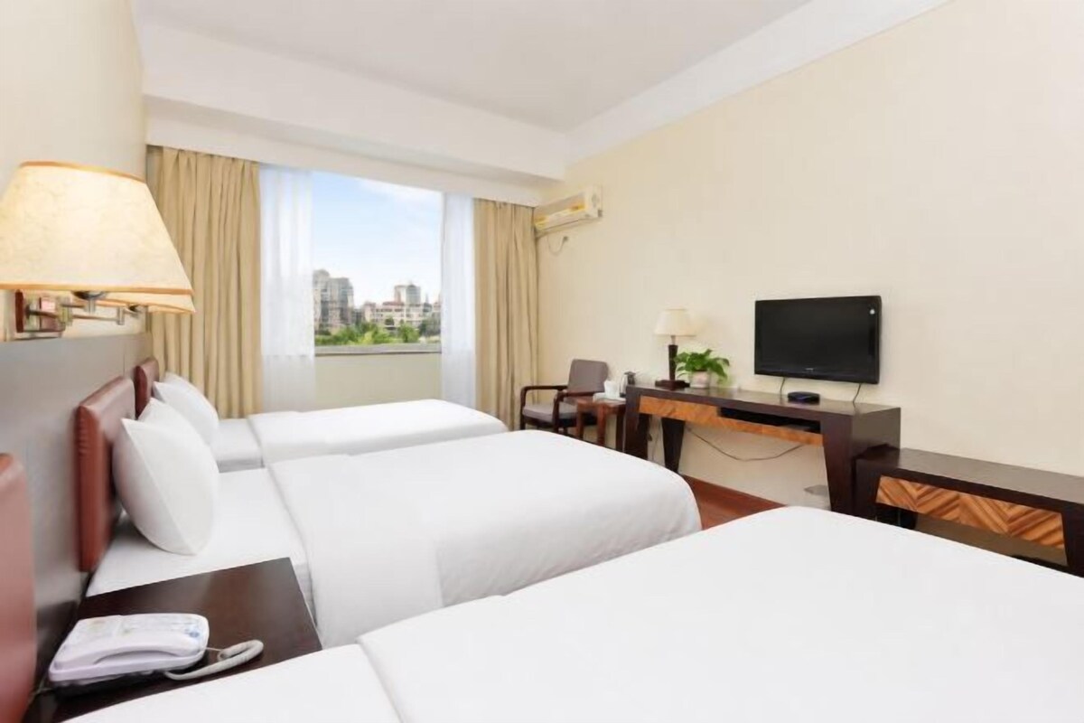 Una habitació d'hotel amb dos llits, un escriptori amb televisió i una finestra que donava a una vista de la ciutat.