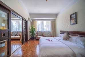 Une chambre d’hôtel avec un grand lit, un canapé, une plante en pot et une vue sur la ville.