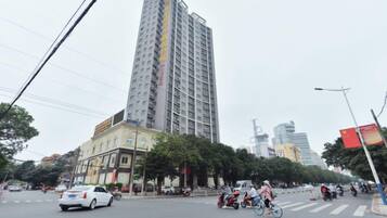 A multi-story building with a modern design, located in an urban setting with trees and other buildings around.