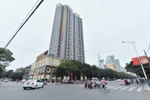 Un edificio moderno de varios pisos, situado en un entorno urbano con árboles y otros edificios.